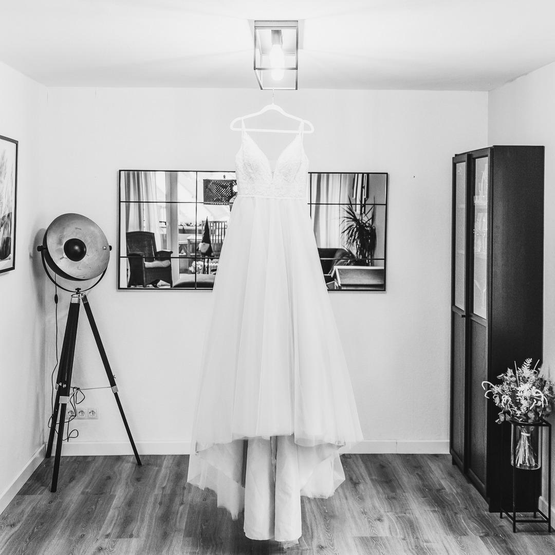 Brautkleid hängt an der Deckenlampe im Wohnzimmer - Aufnahme in Schwarzweiß