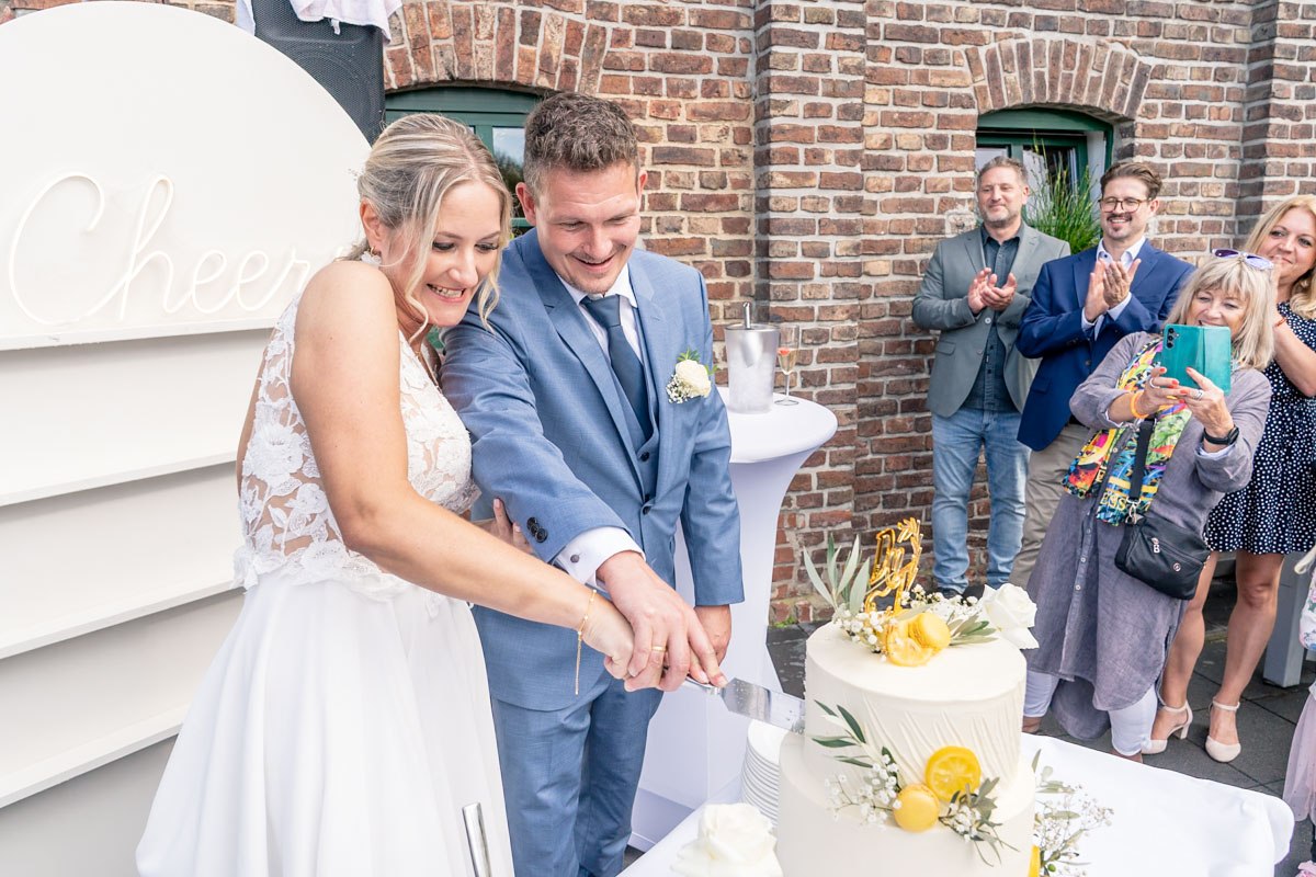 Brautpaar schneiden den Hochzeitstorte an. Seine Hand ist oben