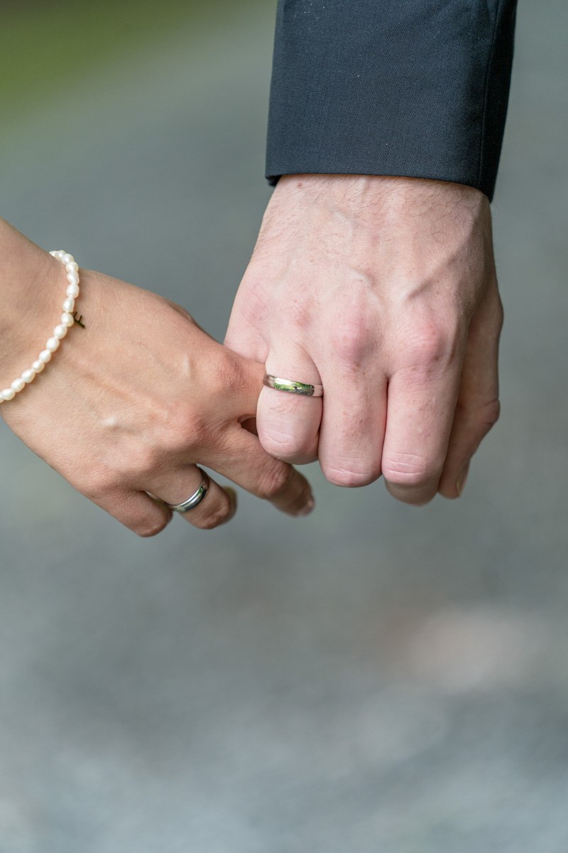 Nahaufnahme der Hochzeitsringe auf den Händen, feierliche Details